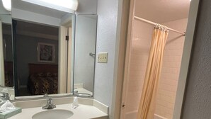 Ein Badezimmer mit zwei Waschbecken, einem Spiegel, einer Toilette und einer Dusche mit Duschvorhang.