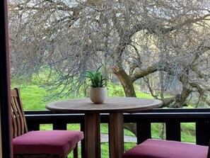 A round wooden table with a potted plant, two cushioned chairs, and a view of a tree-lined outdoor area. - 10 minutes to Sequoia Park Entrance/Hot Tub/Fire Pit/Pet Friendly/Mountain Views (Three Rivers)