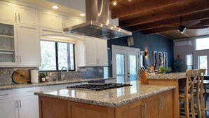 A spacious kitchen with a large island, wooden cabinets, and a modern stove. - 10 minutes to Sequoia Park Entrance/Hot Tub/Fire Pit/Pet Friendly/Mountain Views (Three Rivers)