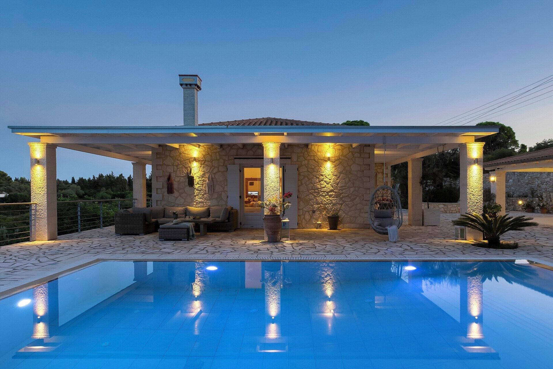 A covered outdoor area with a pool, stone walls, and a seating area with cushions.