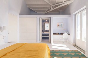 Una camera da letto con un letto, una scrivania, una sedia e un bagno parzialmente visibile.
