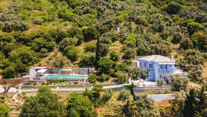 Une propriété située sur la côte, dotée d’une piscine, de murs en pierre et d’une grande maison avec un toit bleu.