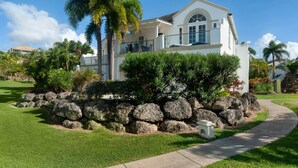 A two-story house with a stone foundation, surrounded by a well-maintained lawn and palm trees. - Royal Villa - Royal Westmoreland - Modern Tropical Villa (Saint James)
