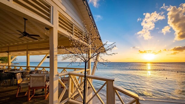 A wooden deck with outdoor seating, overlooking a body of water during sunset. - Royal Villa - Royal Westmoreland - Modern Tropical Villa (Saint James)