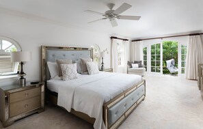 A bedroom with a large bed, a nightstand, a lamp, and a ceiling fan.
