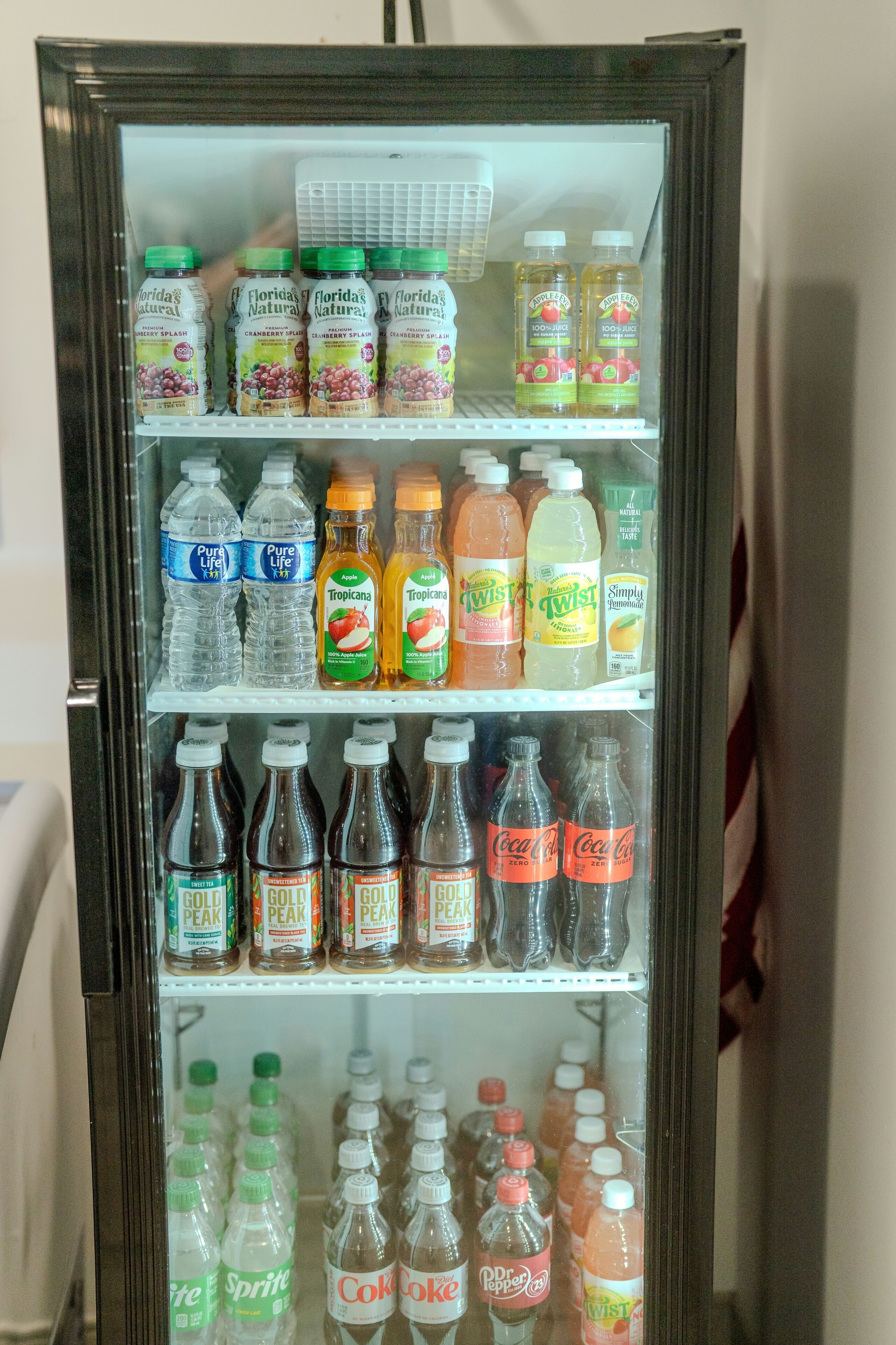 A beverage refrigerator stocked with various drinks including Florida's Natural, Tropicana, and Coca-Cola.