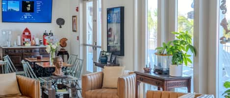 A living room with leather sofas, a glass coffee table, a flat-screen TV, and a potted plant.