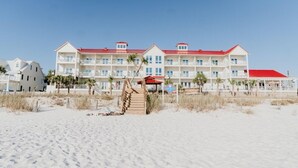 Un hôtel situé en bord de mer, avec plusieurs étages, un toit rouge et un escalier menant à la plage.