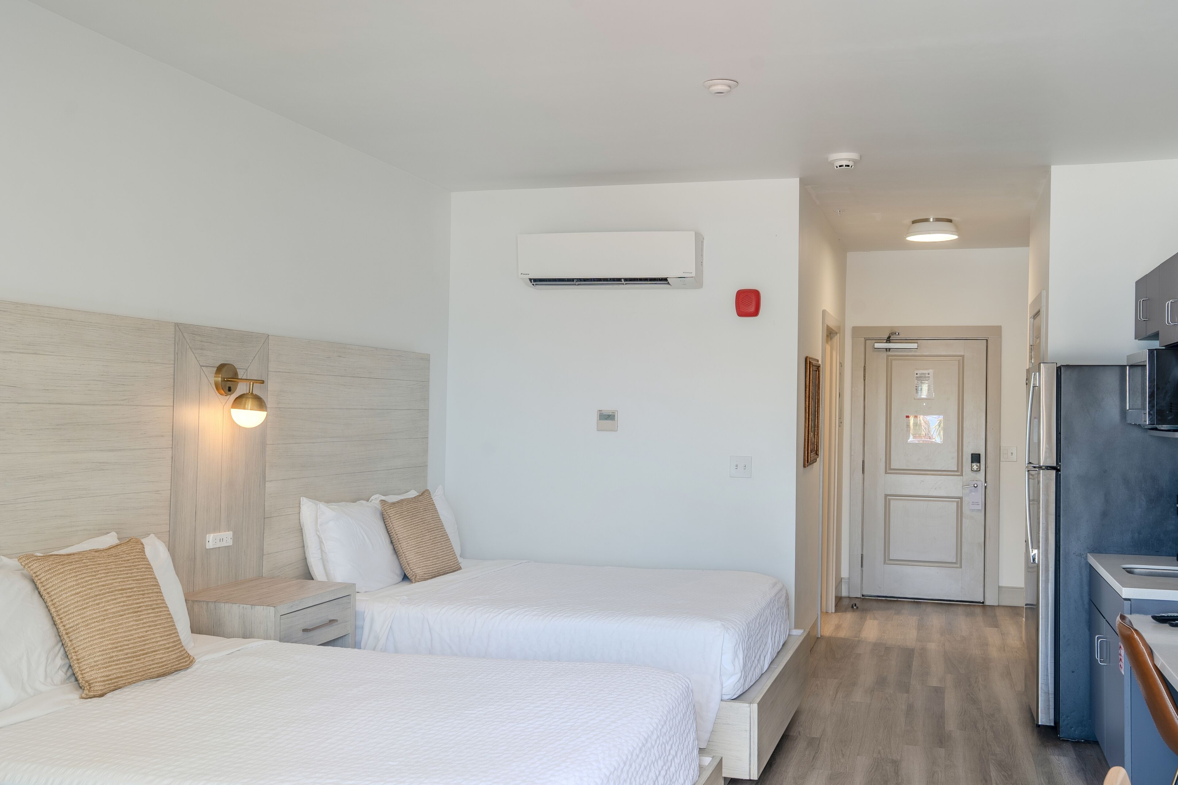 Une chambre d’hôtel avec deux lits, une kitchenette et une salle de bain.