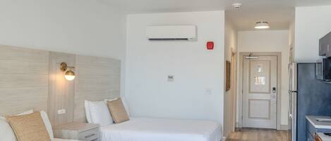 A hotel room with two beds, a kitchenette, and a bathroom.