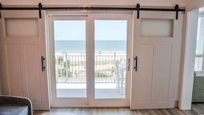Une chambre dotée d’une porte-fenêtre coulissante donnant sur un balcon avec vue sur la plage.