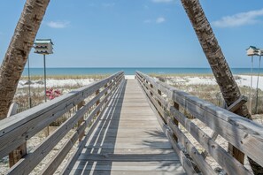 A wooden boardwalk leading to a beach with clear skies. - Driftwood Inn  (Mexico Beach)