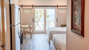 Une chambre d’hôtel équipée d’un lit, d’un bureau, d’une chaise, d’un réfrigérateur et d’une porte coulissante donnant sur le balcon.