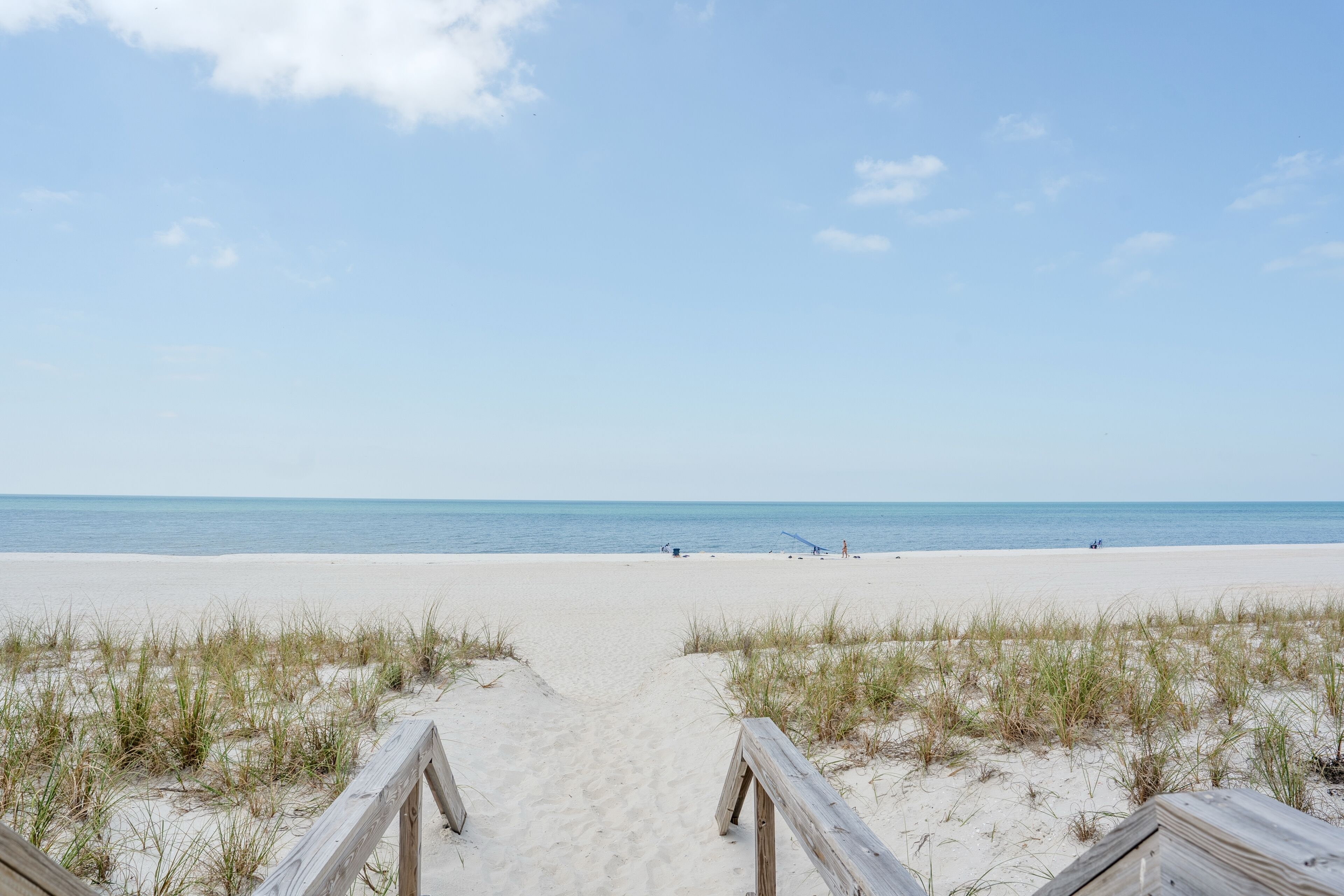 Ein Strandweg, der zum Meer führt, mit Holzgeländern.