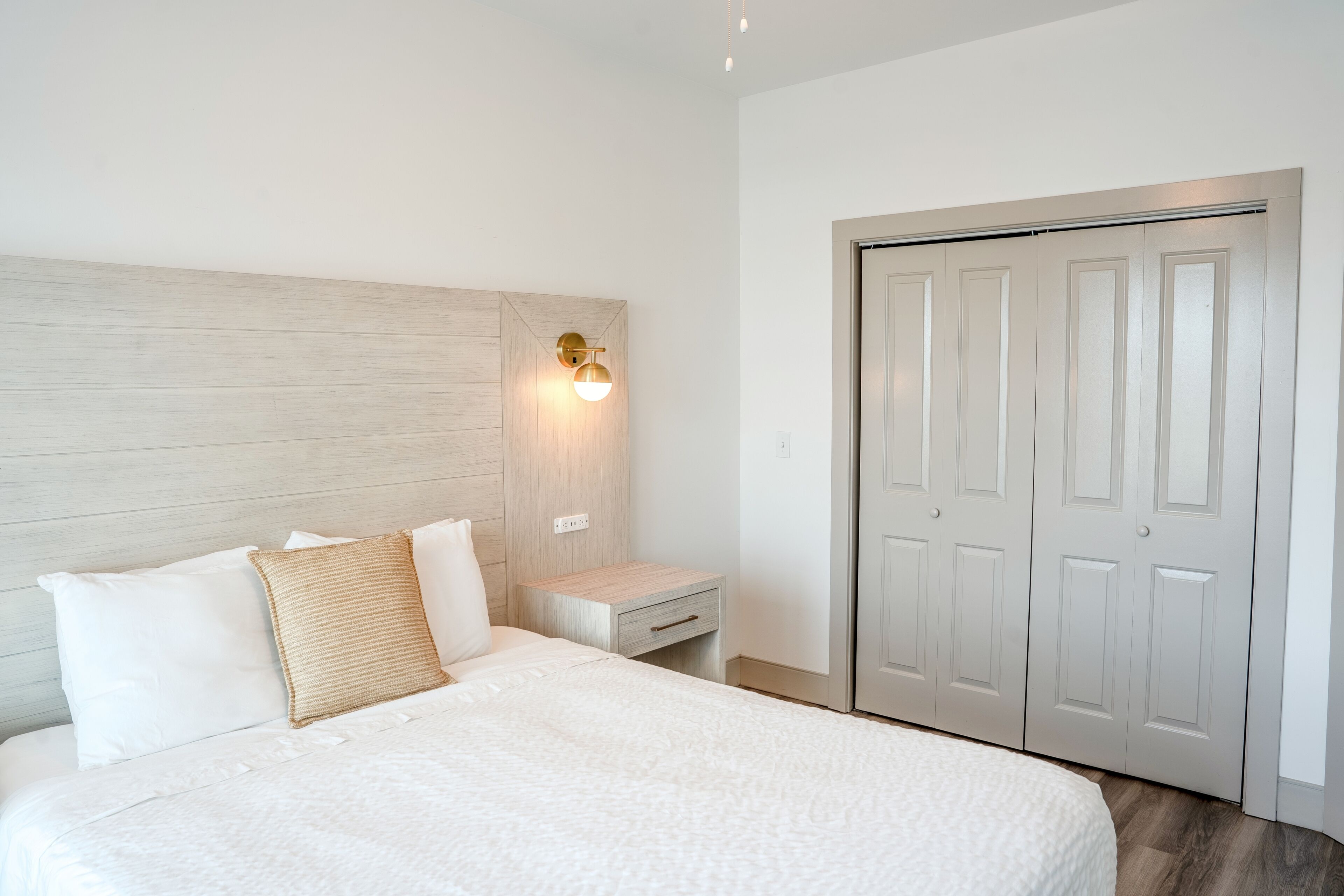 A bedroom with a bed, bedside table, lamp, and a wardrobe.