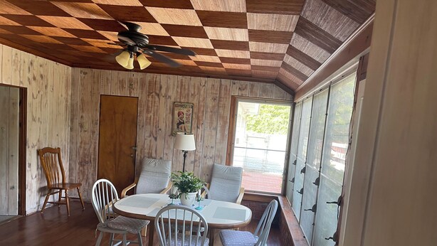 Un espace repas doté d’un plafond en bois, d’un ventilateur de plafond, d’une table avec des chaises, d’une plante en pot et d’une fenêtre donnant sur l’extérieur.