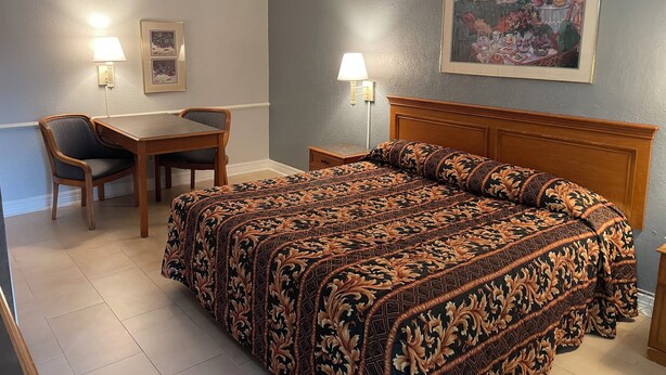 Une chambre d’hôtel équipée d’un lit, d’un bureau, d’une chaise et de deux lampes fixées au mur.