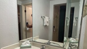 Une salle de bain avec un lavabo blanc, un miroir et un porte-serviettes.