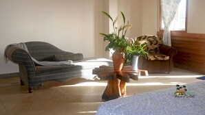 A room with a grey sofa, a wooden coffee table with a plant, and a bed with a white bedspread. - Island View Estate with a spectacular view and privacy, creating tranquility. (Kingstown)