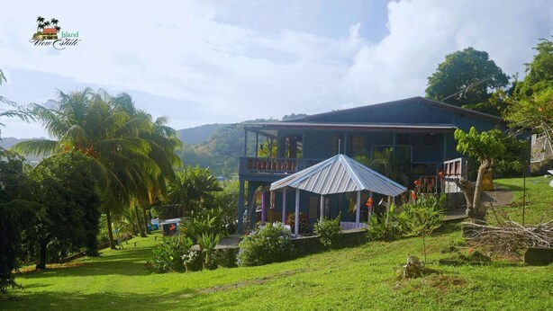 A two-story building with a covered outdoor area, surrounded by lush greenery and palm trees. - Island View Estate with a spectacular view and privacy, creating tranquility. (Kingstown)