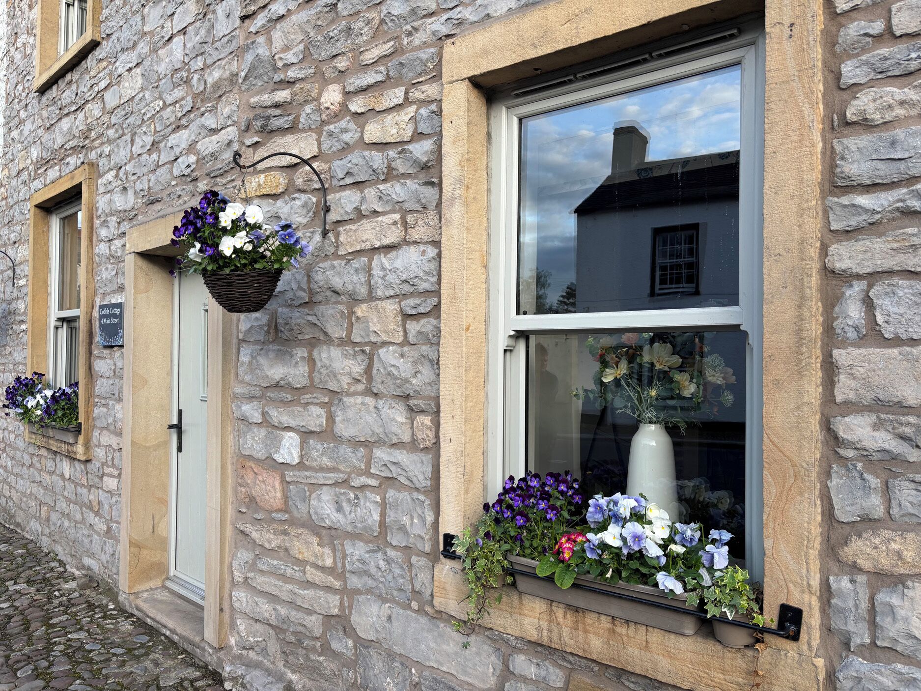 En bygning i sten med et vindue, en dør og blomsterkasser.