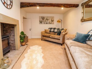 A cozy living room with a fireplace, a sofa, a rug, and a painting on the wall. - Cobble Cottage (Clitheroe)