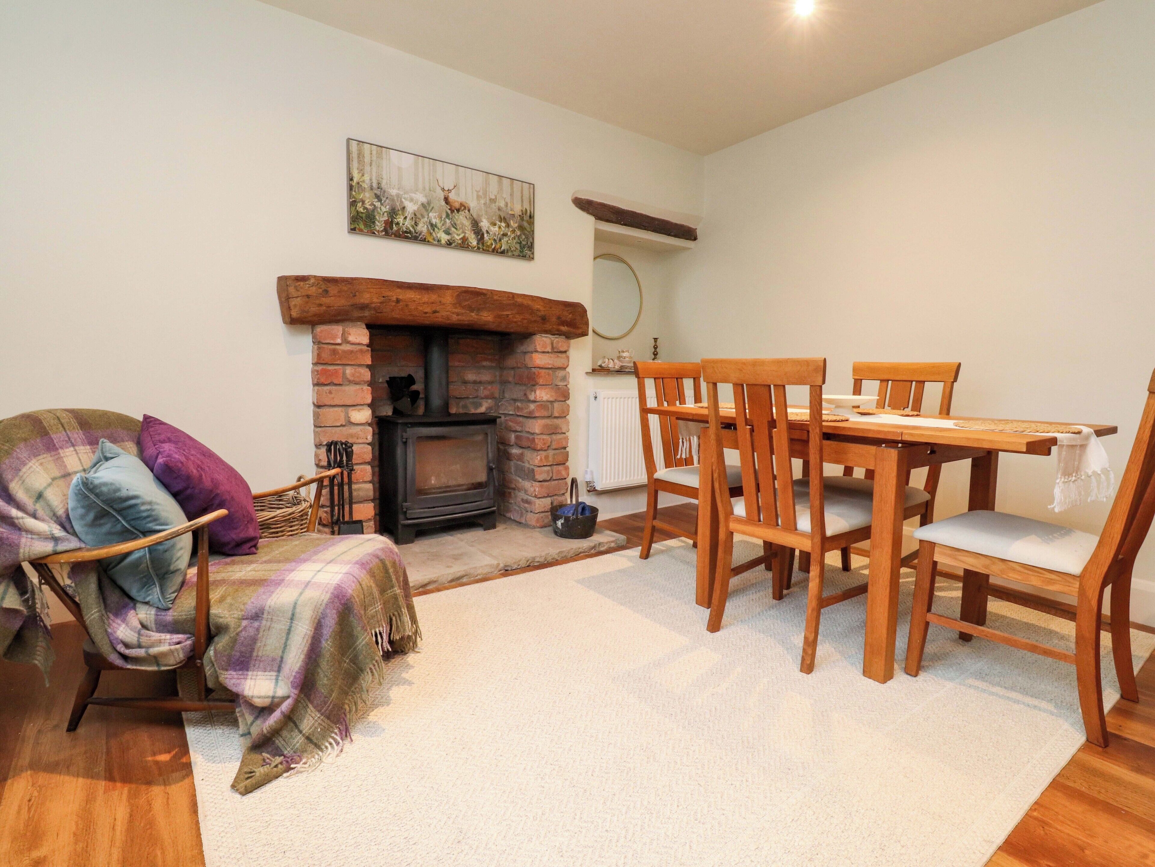 A cozy living room with a fireplace, wooden furniture, and a plaid blanket on a chair.