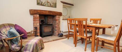 A cozy living room with a fireplace, wooden furniture, and a plaid blanket on a chair.