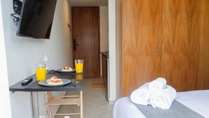 Ein Hotelzimmer mit Bett, Schreibtisch mit Frühstück, Fernseher und Kleiderschrank.