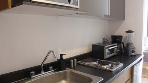 Eine moderne Küche mit einer Spüle aus Edelstahl, einer Mikrowelle, einem Toaster und einem Mixer auf der Arbeitsfläche.