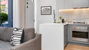 A modern kitchen with a built-in oven, a white countertop, and a pendant light. - Alto Livello 304 - One Bedroom Apartment, Sleeps 2 (Cape Town)