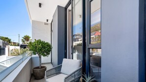 A balcony with a wicker chair and a potted plant. - Alto Livello 304 - One Bedroom Apartment, Sleeps 2 (Cape Town)