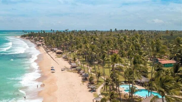 A beach resort with a swimming pool, palm trees, and a view of the ocean. - Triplex em Porto de Galinhas a 50m da Praia Maracaipe (Ipojuca)