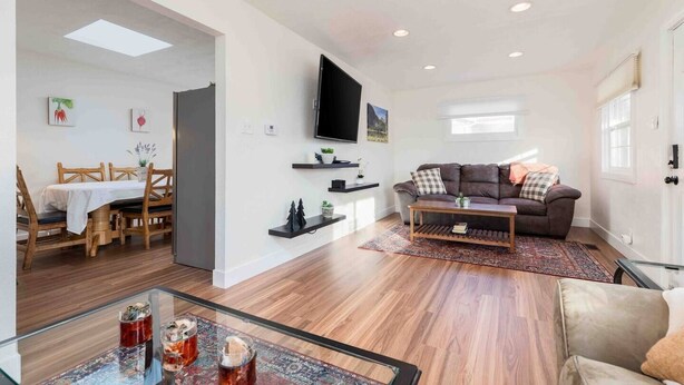 A modern living room with a sofa, coffee table, and a TV mounted on the wall. - Millcreek Basecamp - Pet friendly and Convenient! (Salt Lake City)