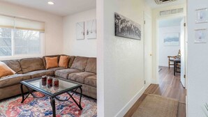 A living room with a sectional sofa, a glass coffee table, and a patterned rug. - Millcreek Basecamp - Pet friendly and Convenient! (Salt Lake City)