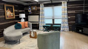 A living room with a sofa, a coffee table, a television, and a window with curtains.