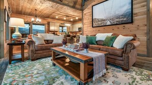 Una sala de estar acogedora con detalles de madera, un ventanal grande y vistas a las montañas.