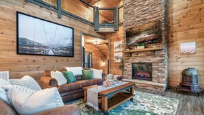 Interior acogedor de una cabaña de troncos con chimenea, un cuadro grande enmarcado y un espacio de descanso cómodo.