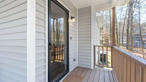 Eine Holzterrasse mit einer Glastür, die zu einer überdachten Veranda führt.