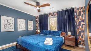 Ein Schlafzimmer mit einem großen Bett, einem Deckenventilator und einem Fenster mit Vorhängen.