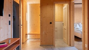 Interior de madera con un banco, una puerta y una cama.
