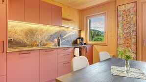 Una cocina moderna con armarios rosados, una encimera de madera y vistas al exterior a través de una ventana.