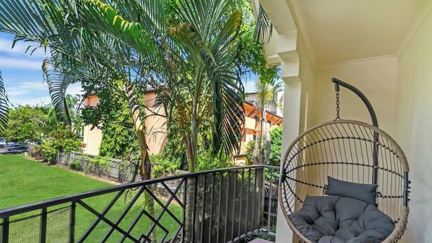 Un balcone con un'amaca, vista su un prato verde e un edificio sullo sfondo.