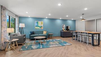 A modern living room with a sofa, coffee table, and dining area with chairs.