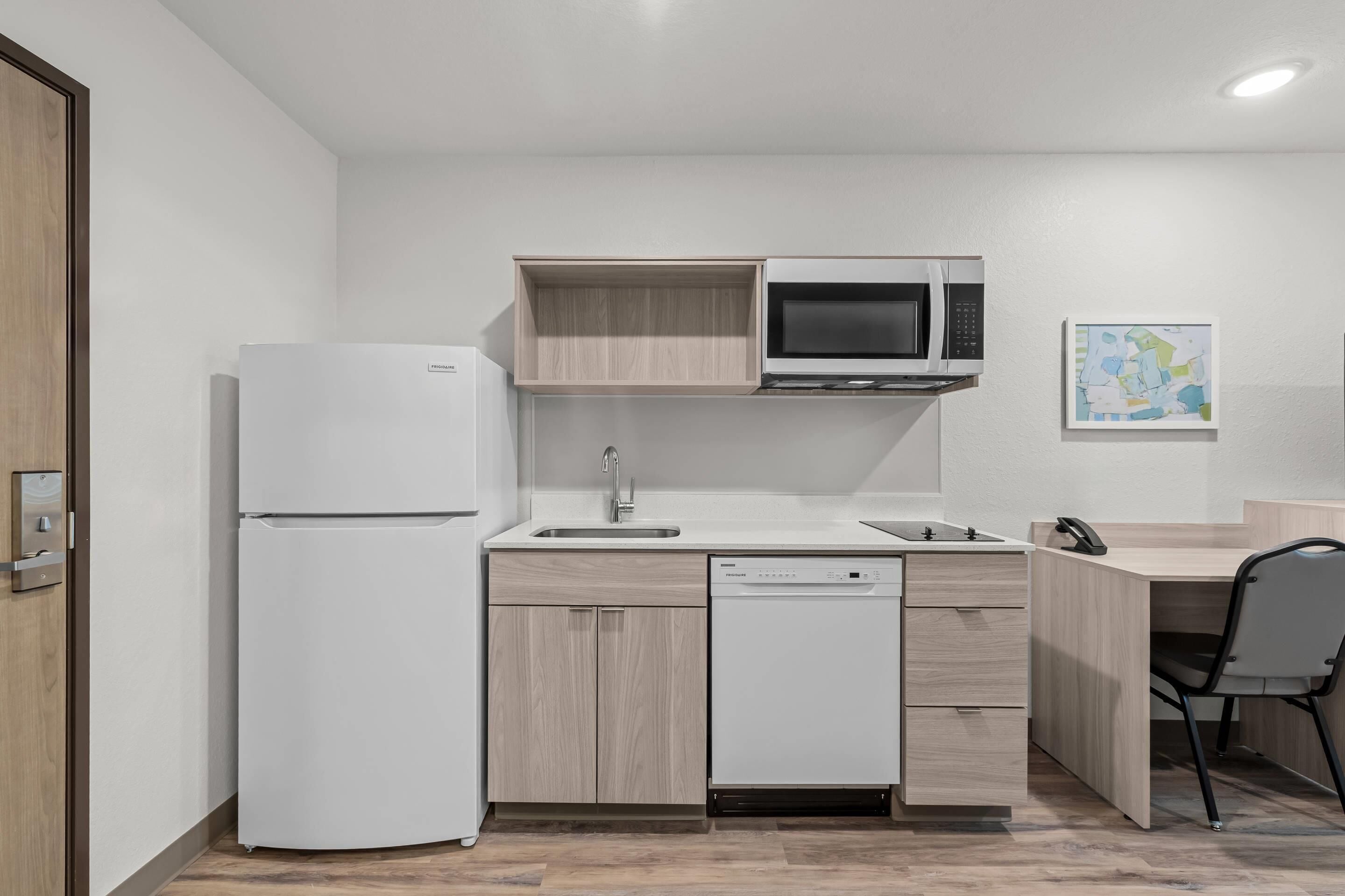 A compact kitchen with a refrigerator, microwave, dishwasher, and a small sink.