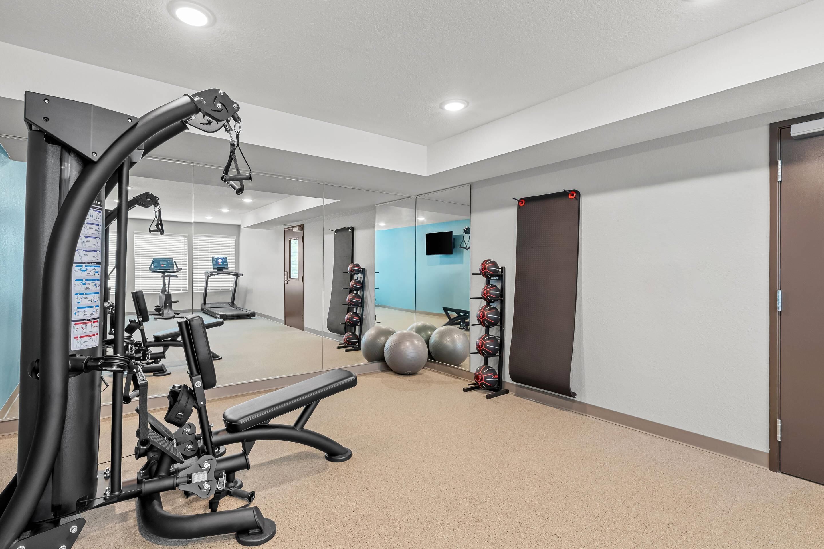 A gym with exercise equipment, a mirror, and exercise balls.