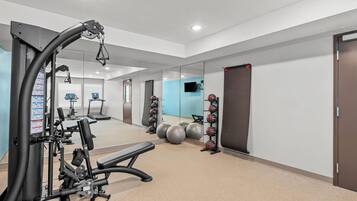 A gym with exercise equipment, a mirror, and exercise balls.