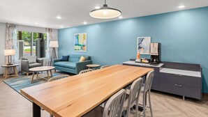 Quarto moderno com uma mesa de jantar de madeira, um sofá, uma máquina de café e um armário.