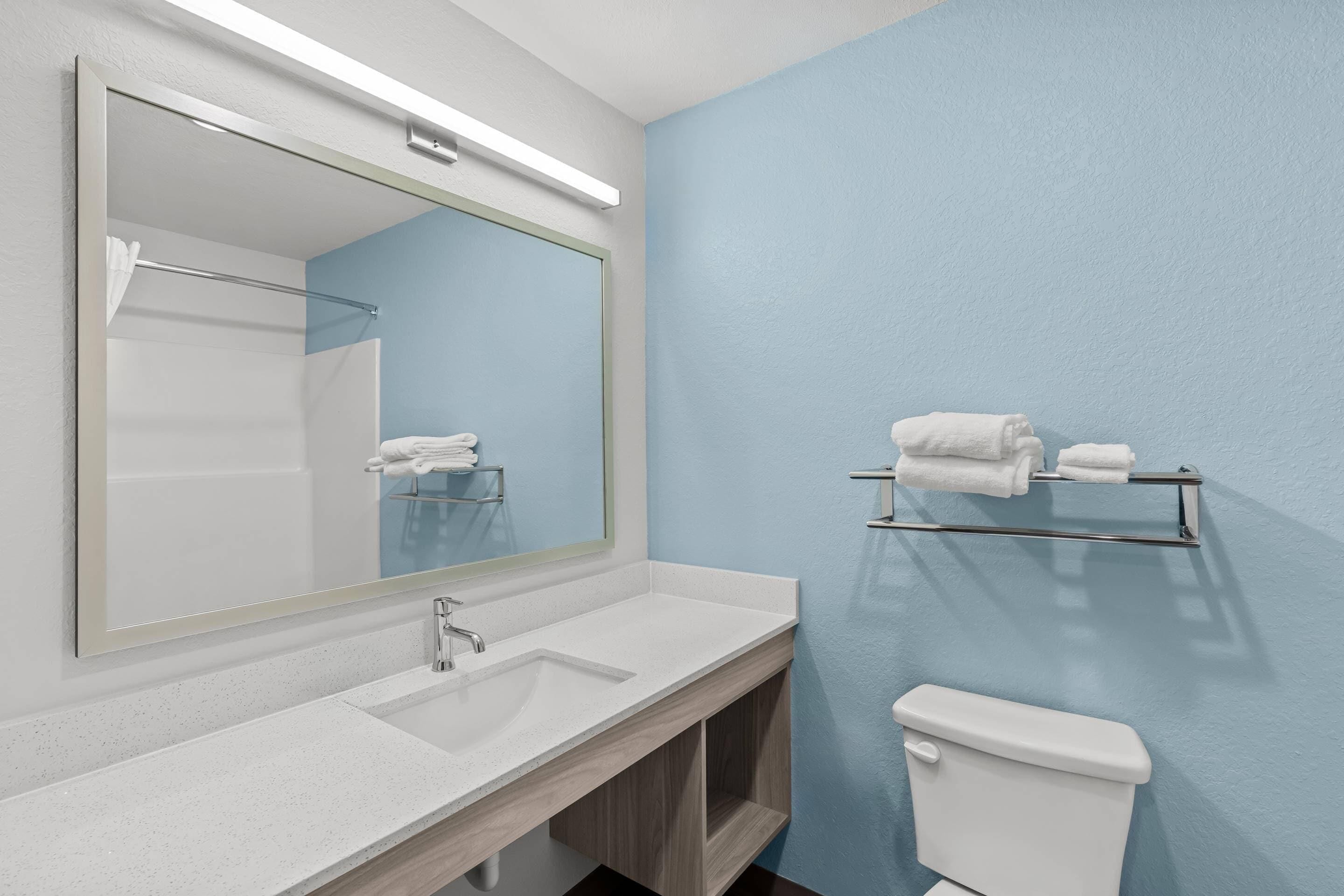 A bathroom with a white sink, a mirror, a towel rack, and a toilet.