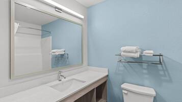 A bathroom with a white sink, a mirror, a towel rack, and a toilet.